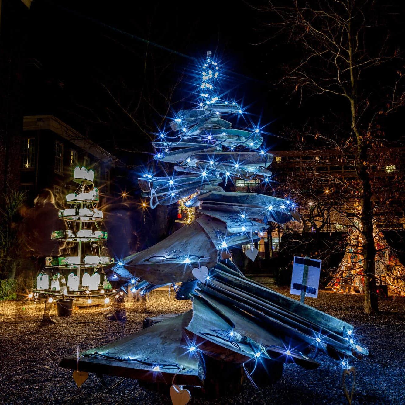 Blauwe draaiende lichtboom met LEDs en warme glasblokkunst op winterplein bij kerstverlichting