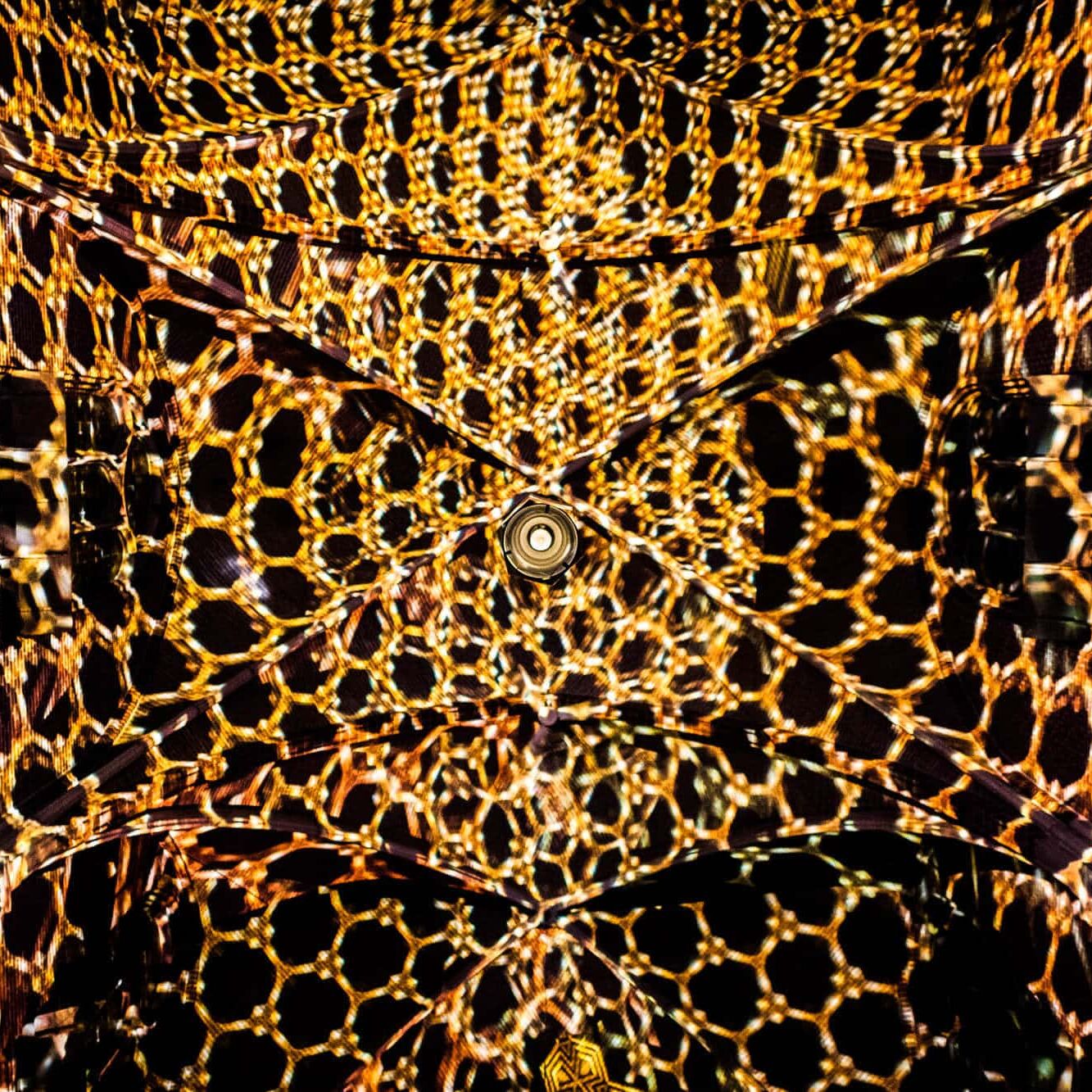 Futuristisch honingraatplafond met centrale hub, diagonale X-lijnen en kaleidoscopisch amber-goud licht.