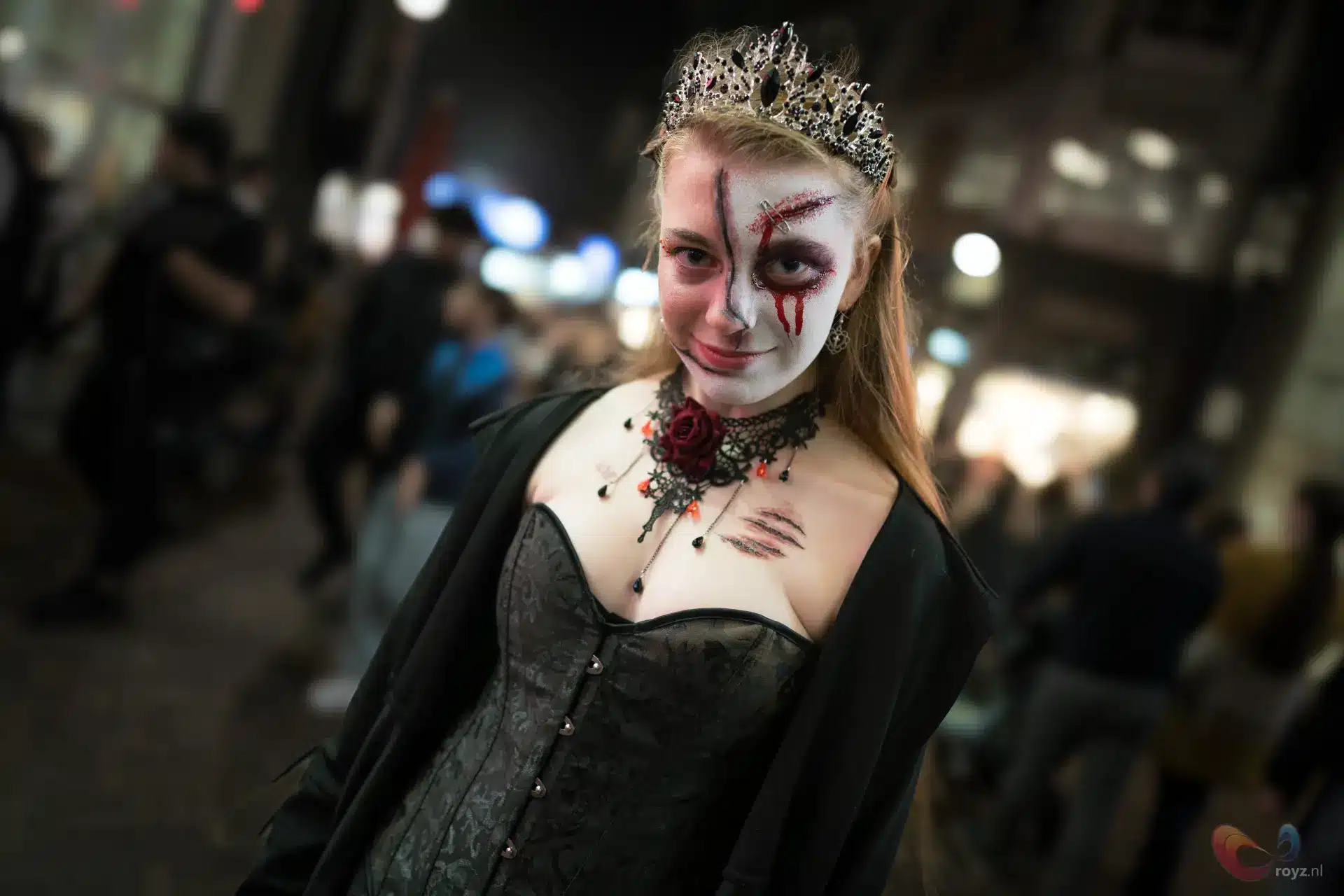 Gothic koningin cosplay op nachtelijke straat met kroon, korset en cape.