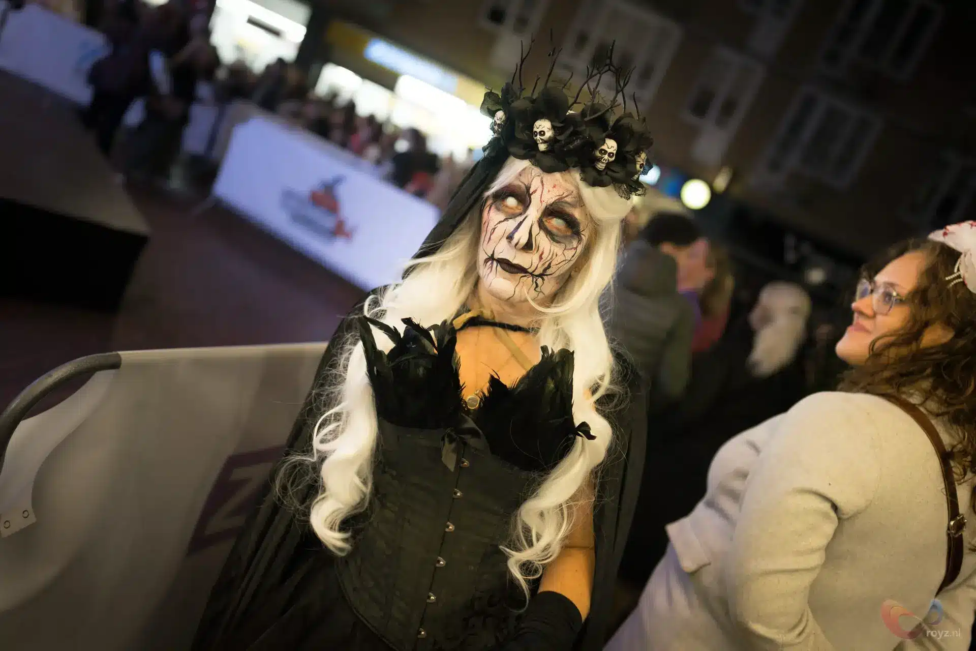 Gothic portret met schedelkrans en zwarte rozen, corset en cape tijdens nachtelijke straatstoet.
