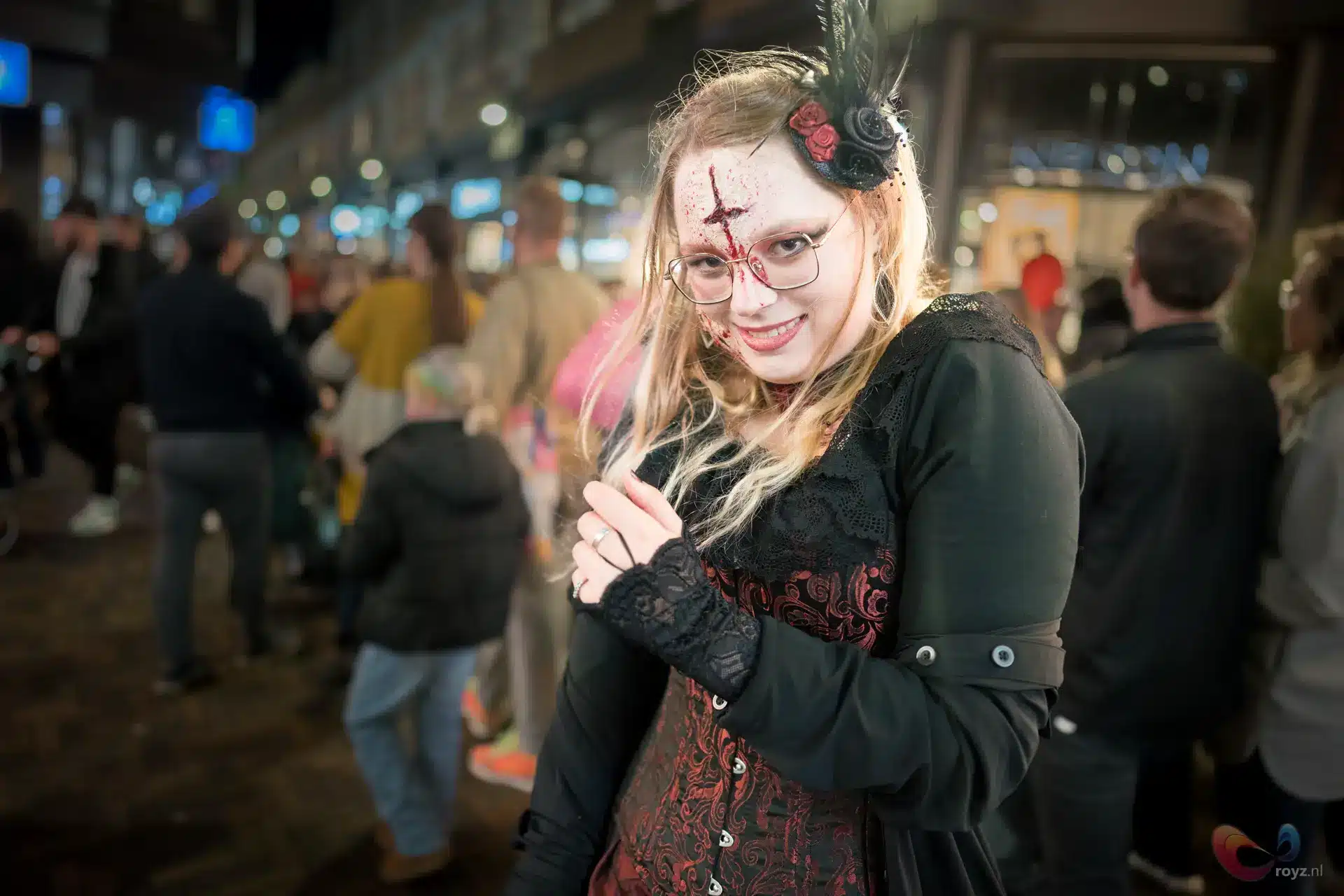 Gothic vrouw met bleke huid en blonde haren op nacht straatfeest, elegante kanten jurk.
