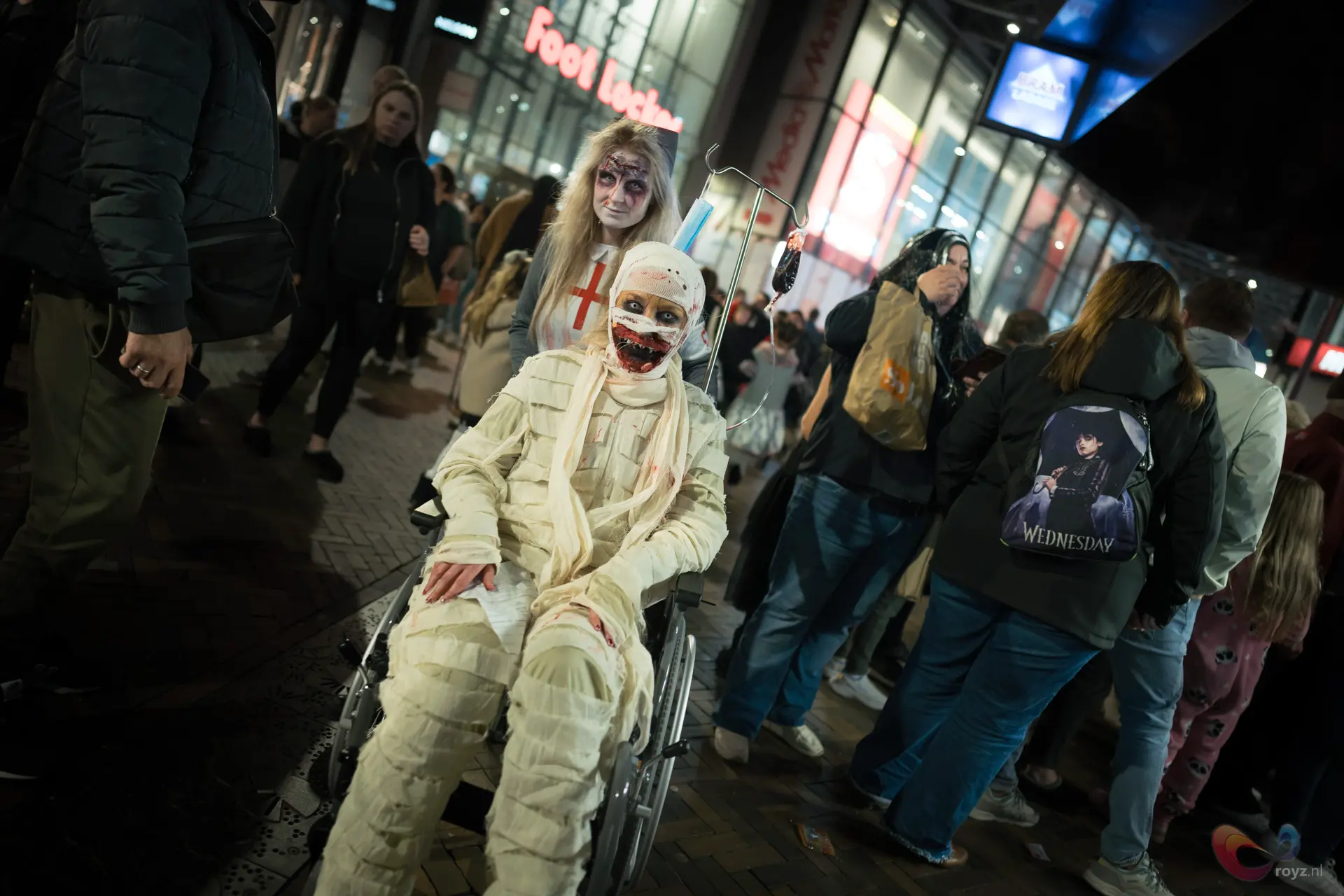 Halloween-cosplay in Zoetermeer: mummie in rolstoel met masker en bleke verpleegkundige.