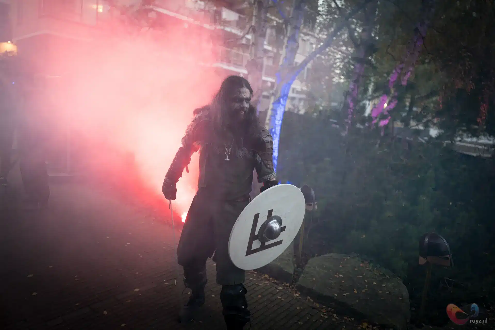 Fantasy strijder met wit rond schild en bontkraag in rokerig stedelijk park.