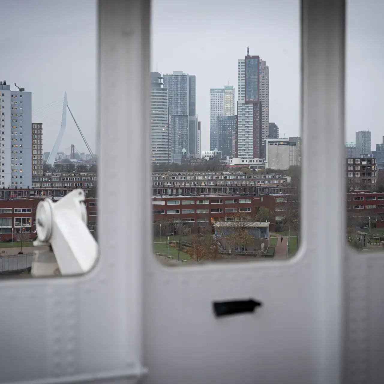 Rotterdamse skyline door drie raamkaders met Erasmusbrug en park.