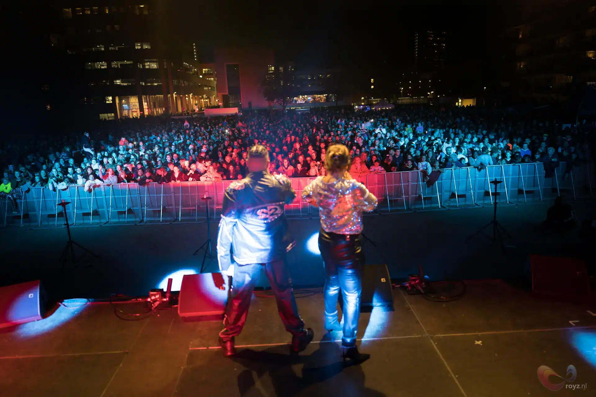Nachtconcert op stadsplein met twee artiesten en kleurrijke podiumlichten
