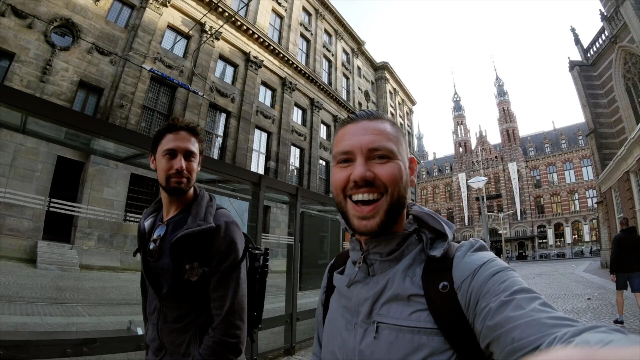 Twee vrienden vloggen op historisch Europees plein met gotische en stenen gevels.