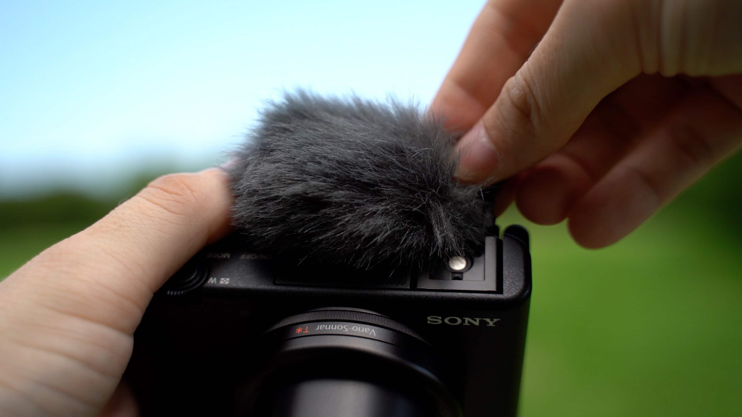Close-up van Sony ZV-1 met extern windscherm microfoon tijdens buitenopnames.