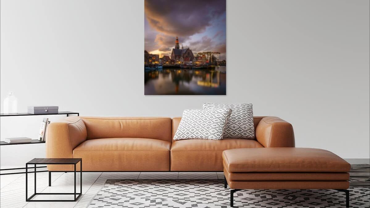 Moderne woonkamer met tan leren bank, grijze muur en havenzicht bij schemering met vuurtoren.