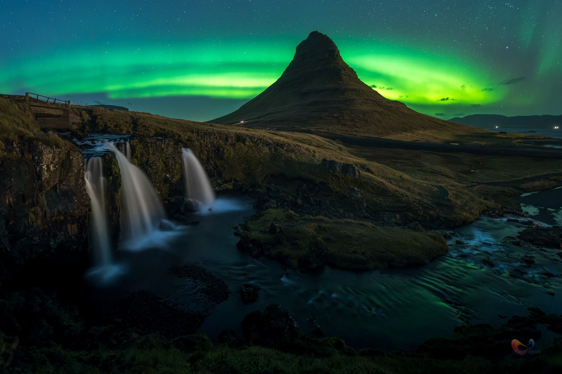 Kirkjufell onder groen noorderlicht met watervallen in IJsland.