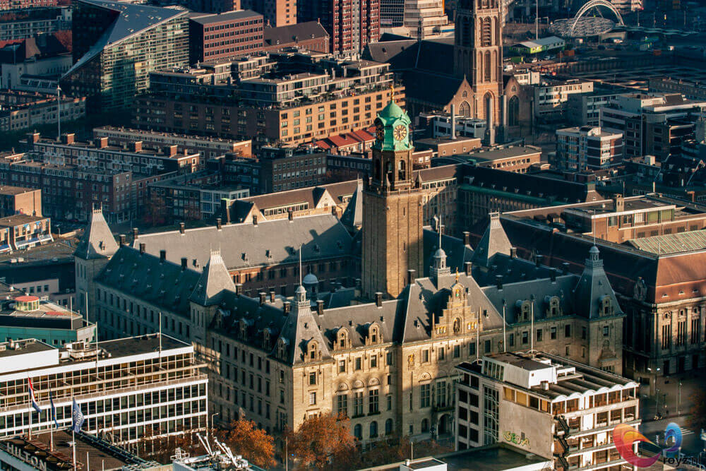 Stadhuis met kloktoren en koperen koepel onder gouden namiddaglicht, historische en moderne stedelijke architectuur.