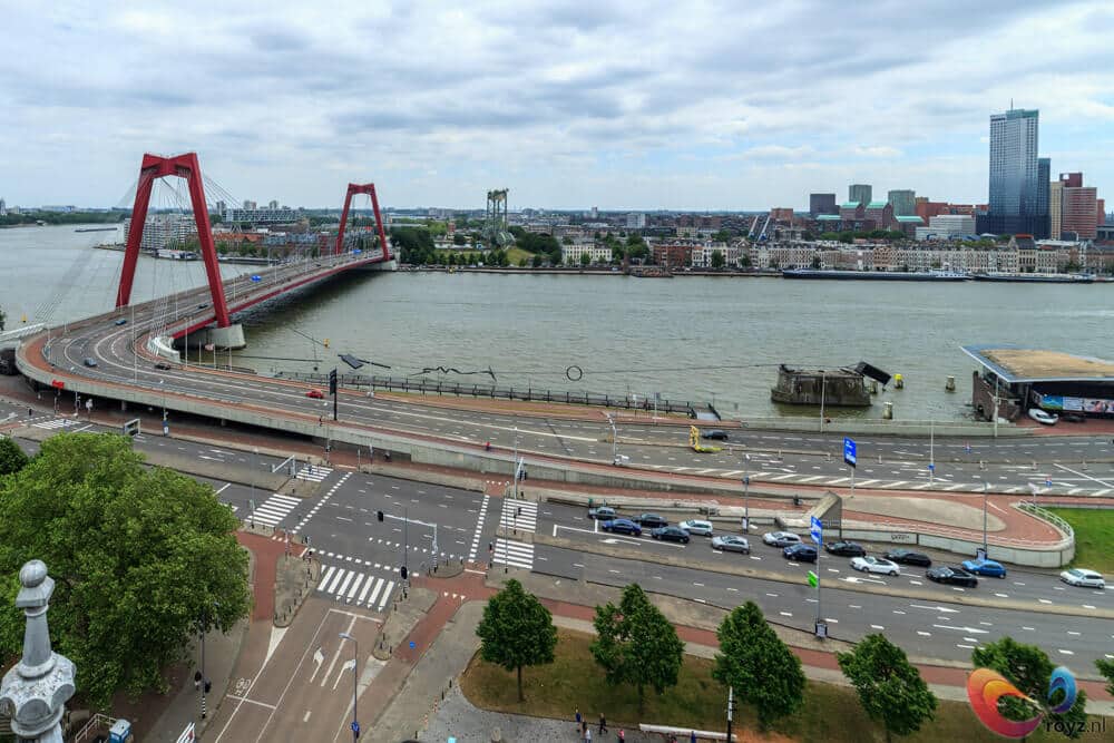 Rode brug over rustige rivier met historisch en modern stadsbeeld in Nederland