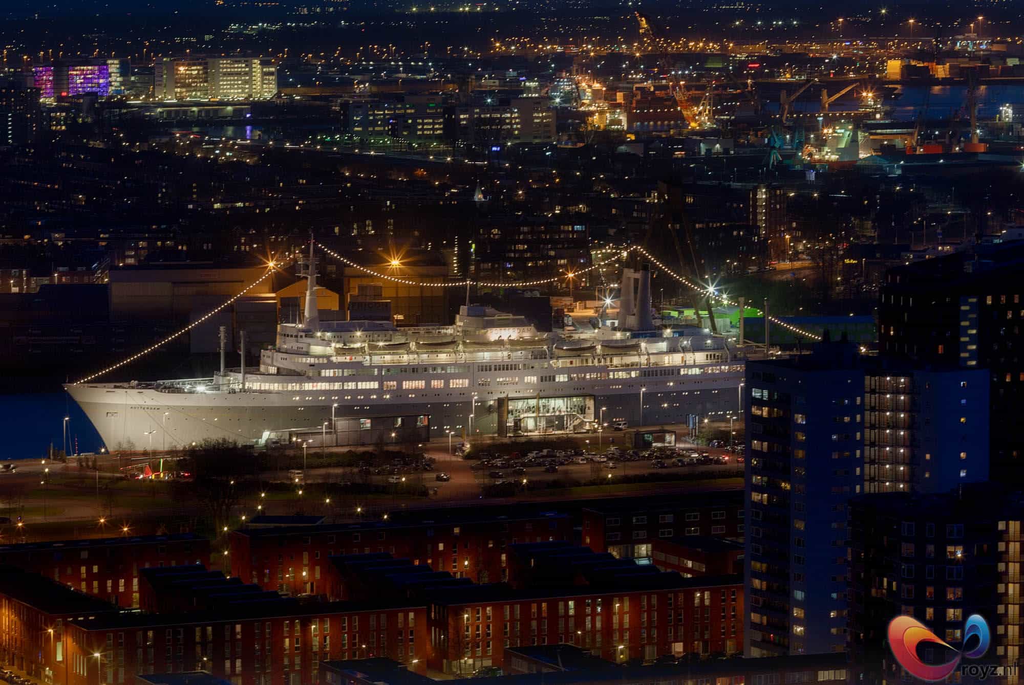 Rotterdamse haven bij nacht met gigantisch cruiseschip en warme verlichting.