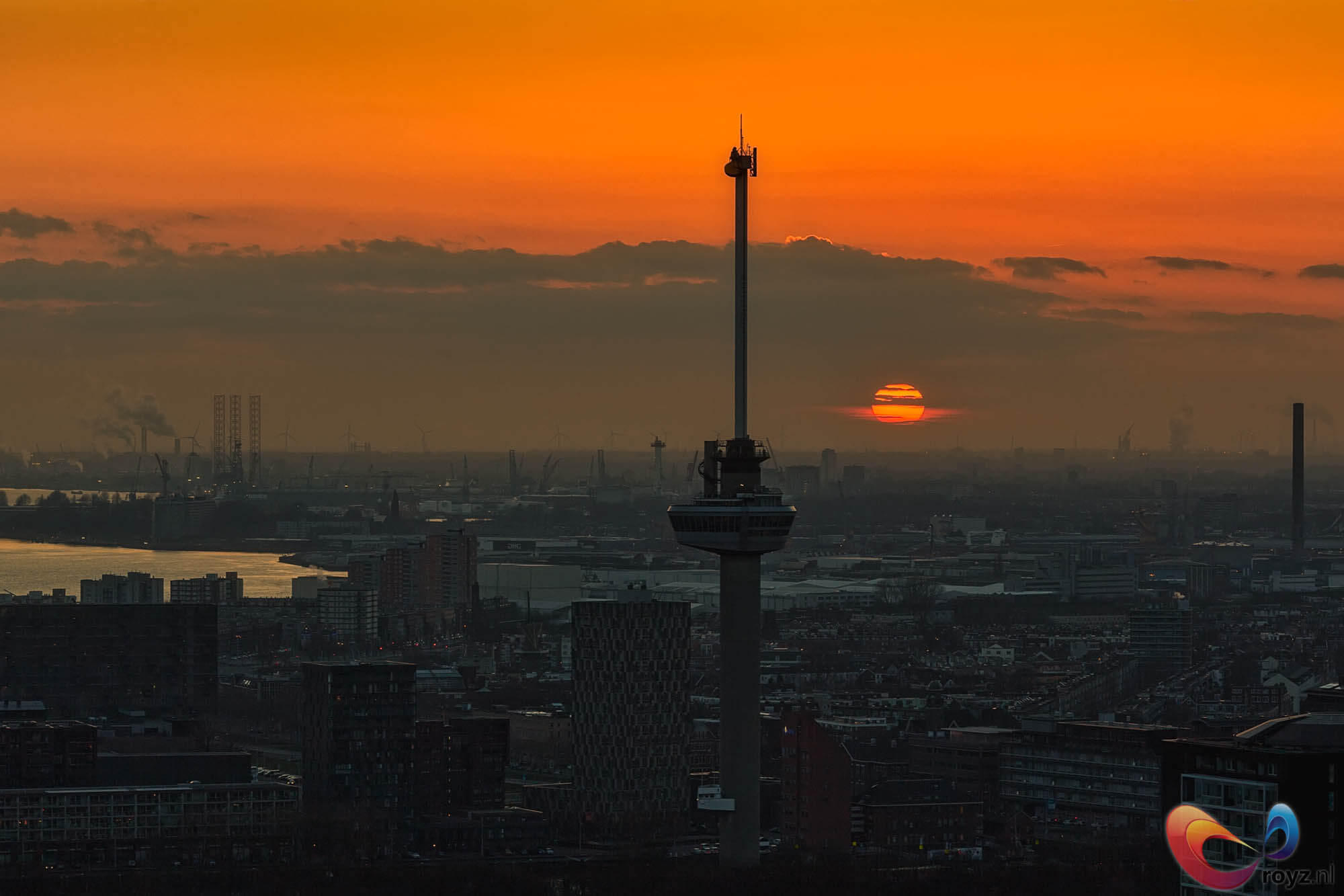 Rotterdam zonsondergang bij Euromast toren: gouden lucht, skyline silhouet en havenkranen langs de rivier.