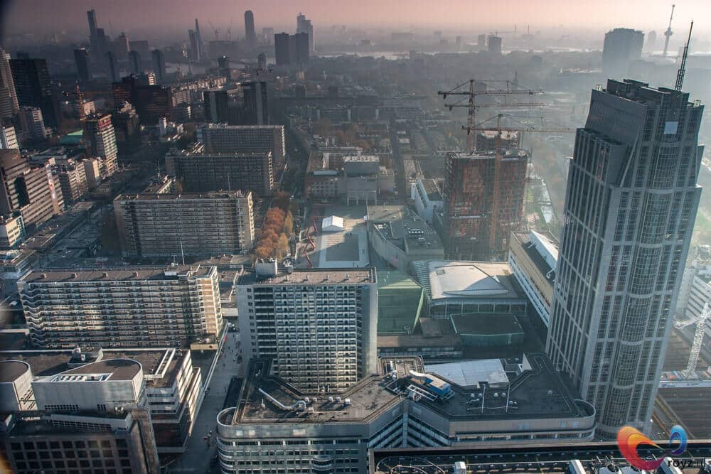 Moderne stadsgezicht bij gouden uur met kranen, glazen torens en gebogen daken.