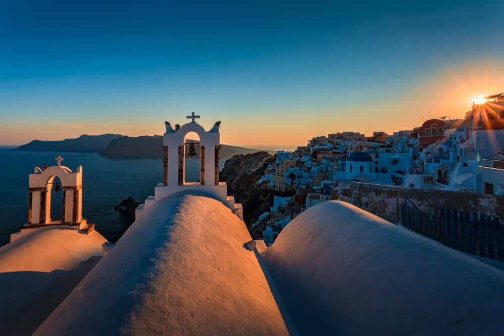 Santorini zonsondergang met witte en blauwe koepels boven zee