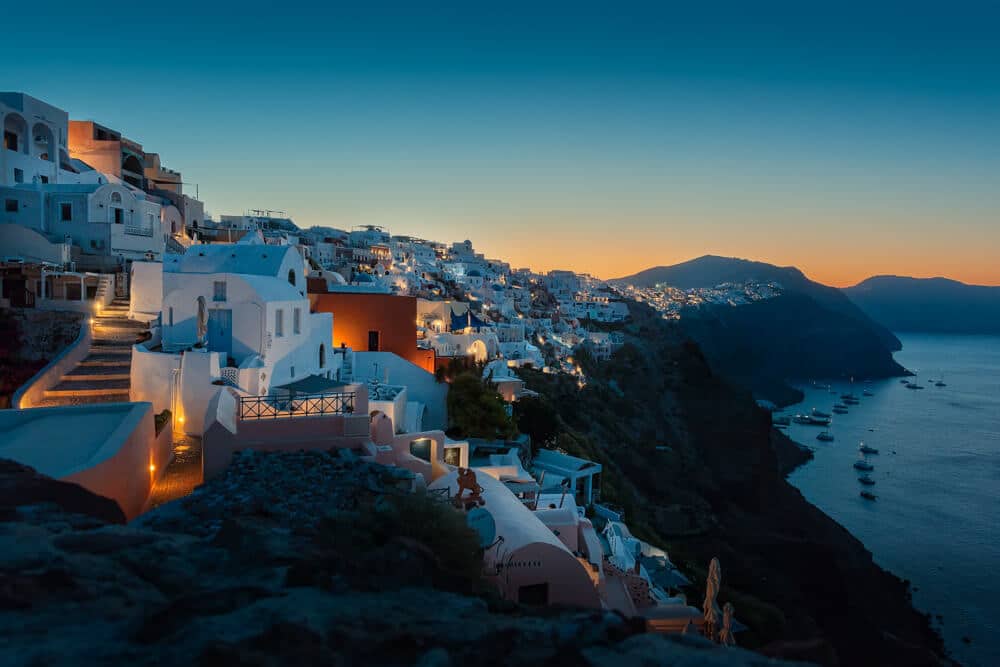 Santorini caldera dorp bij Blauwe Uur met witte huizen en blauwe koepels.