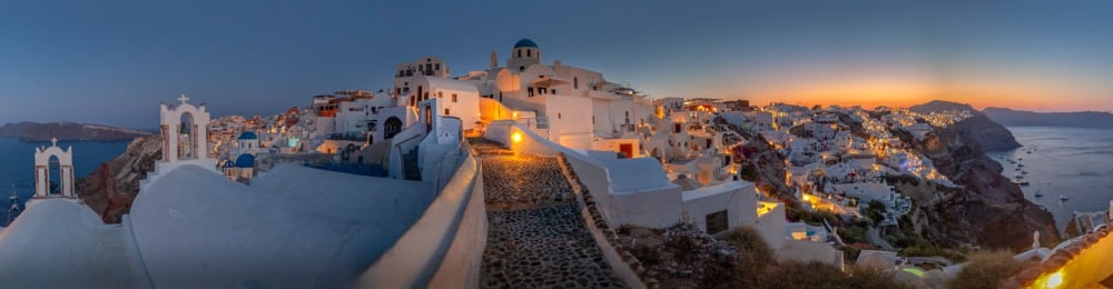 Santorini klifdorp bij schemerlicht met witte Cycladische huizen, blauwe koepels en terrassen.