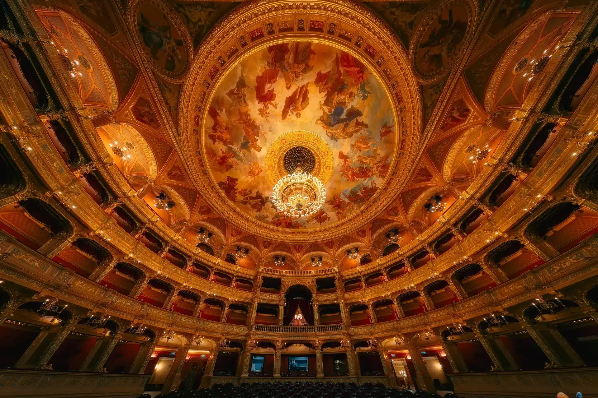 Budapest Operahuis: weelderige gouden zaal met kroonluchter, balkons en frescos.