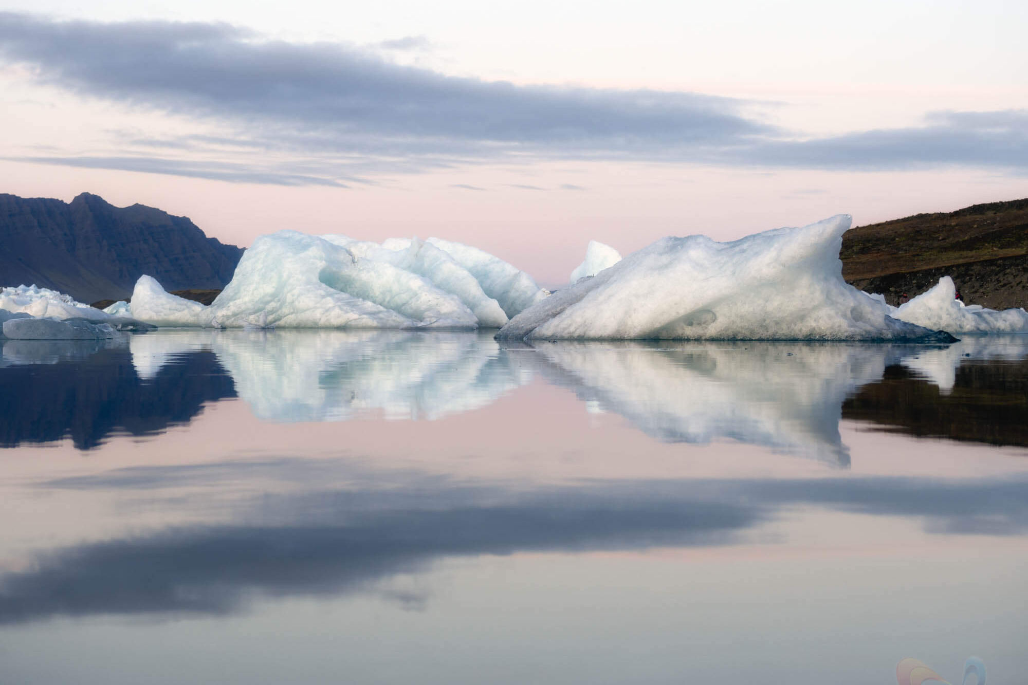 Jökulsárlón ijsbergen bij dageraad op IJsland, kalm water met reflectie.