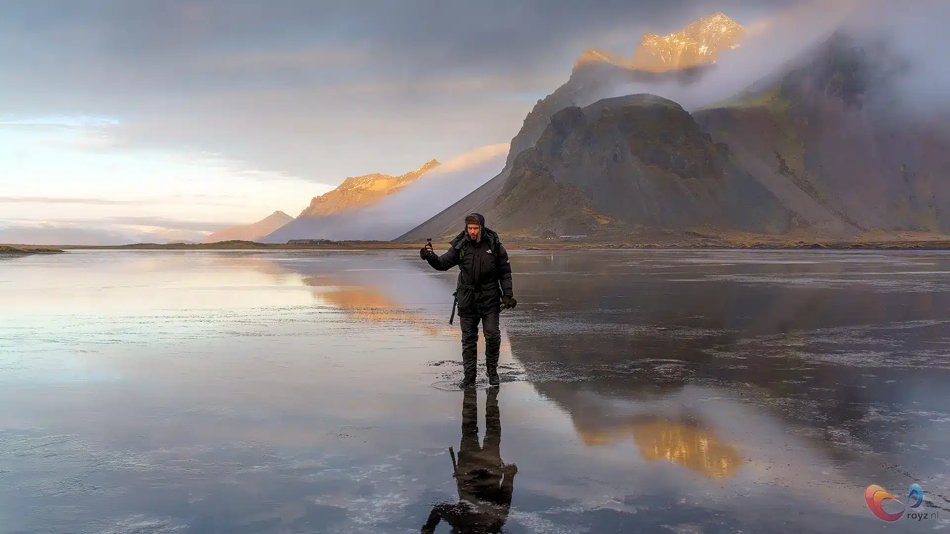 Reiziger op spiegelend water bij IJslandse berg in avondlicht, heldere reflectie.
