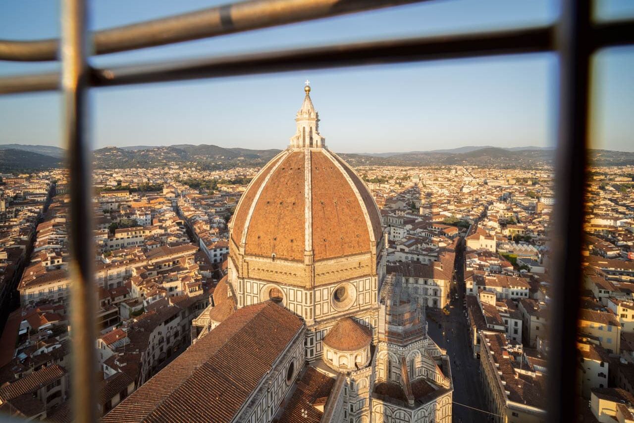 Florence: Brunelleschi-koepel boven rode daken en polychroom marmer, zonovergoten panorama.