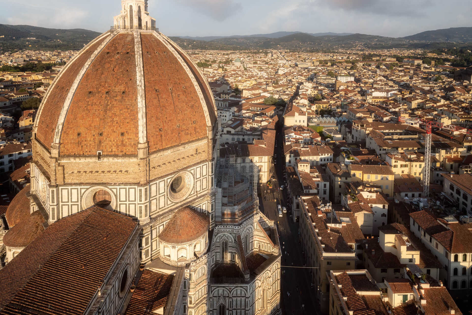 Het Duomo van Florence bij gouden uur met koepel, lantaarn en steigers.