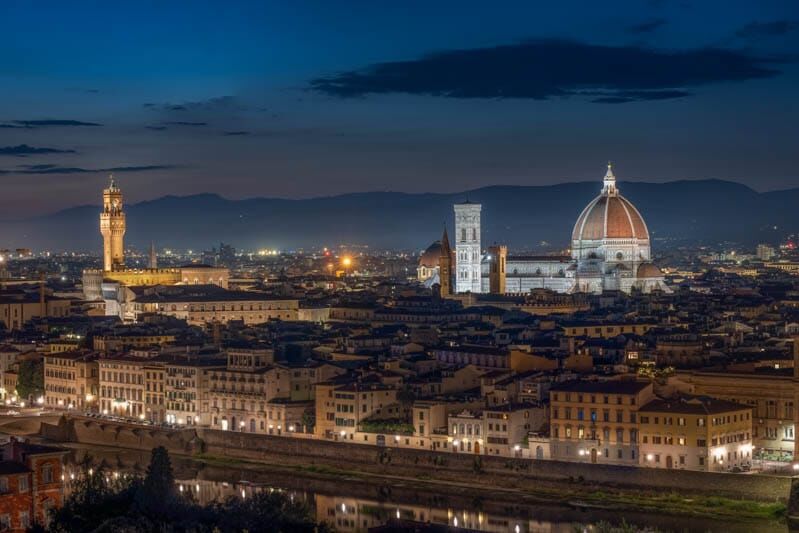 Florence bij nacht langs de Arno met Duomo en Santa Croce in warm licht.