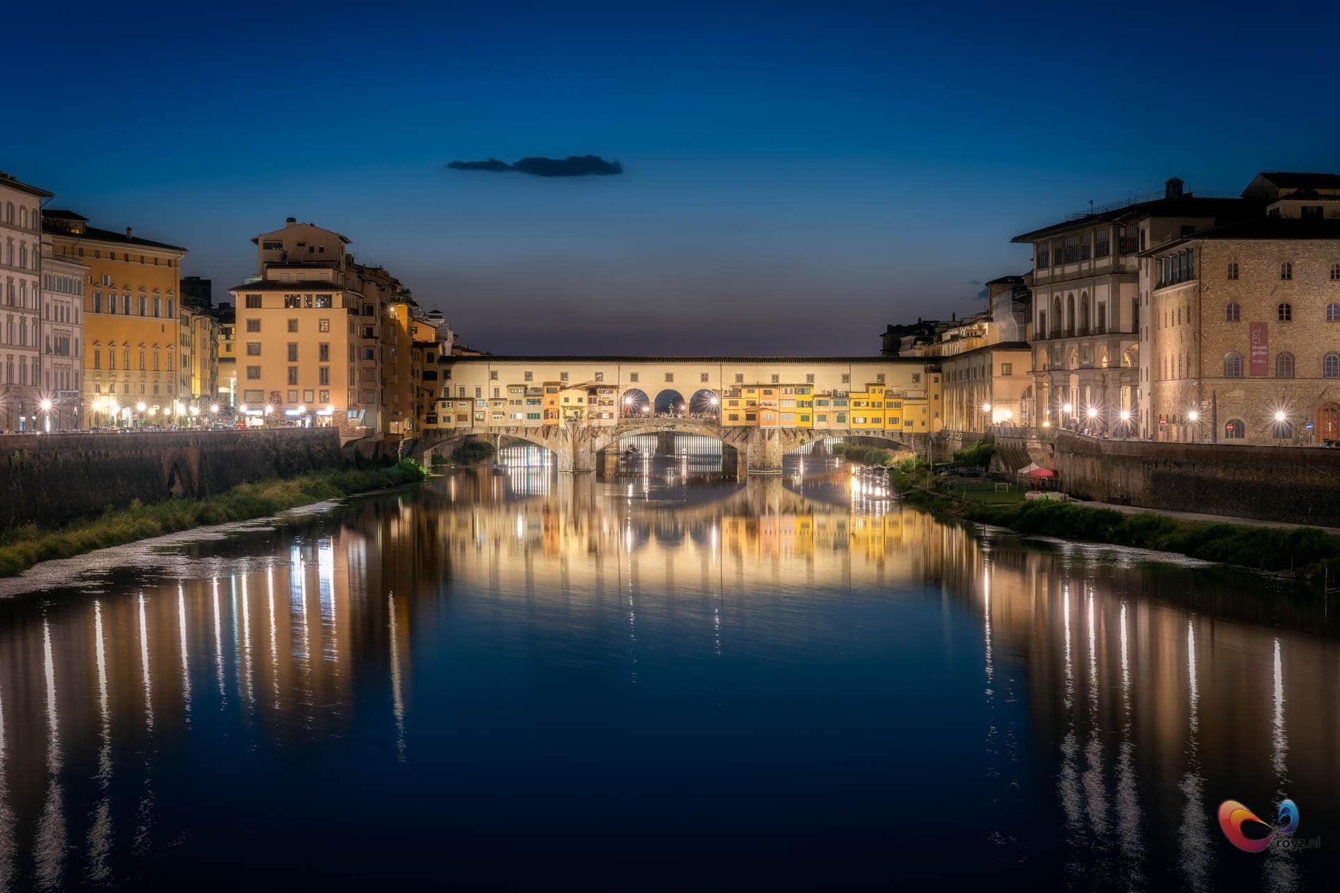 Ponte Vecchio bij schemering aan de Arno in Florence, Italië; water weerspiegelt warme gevellichten.