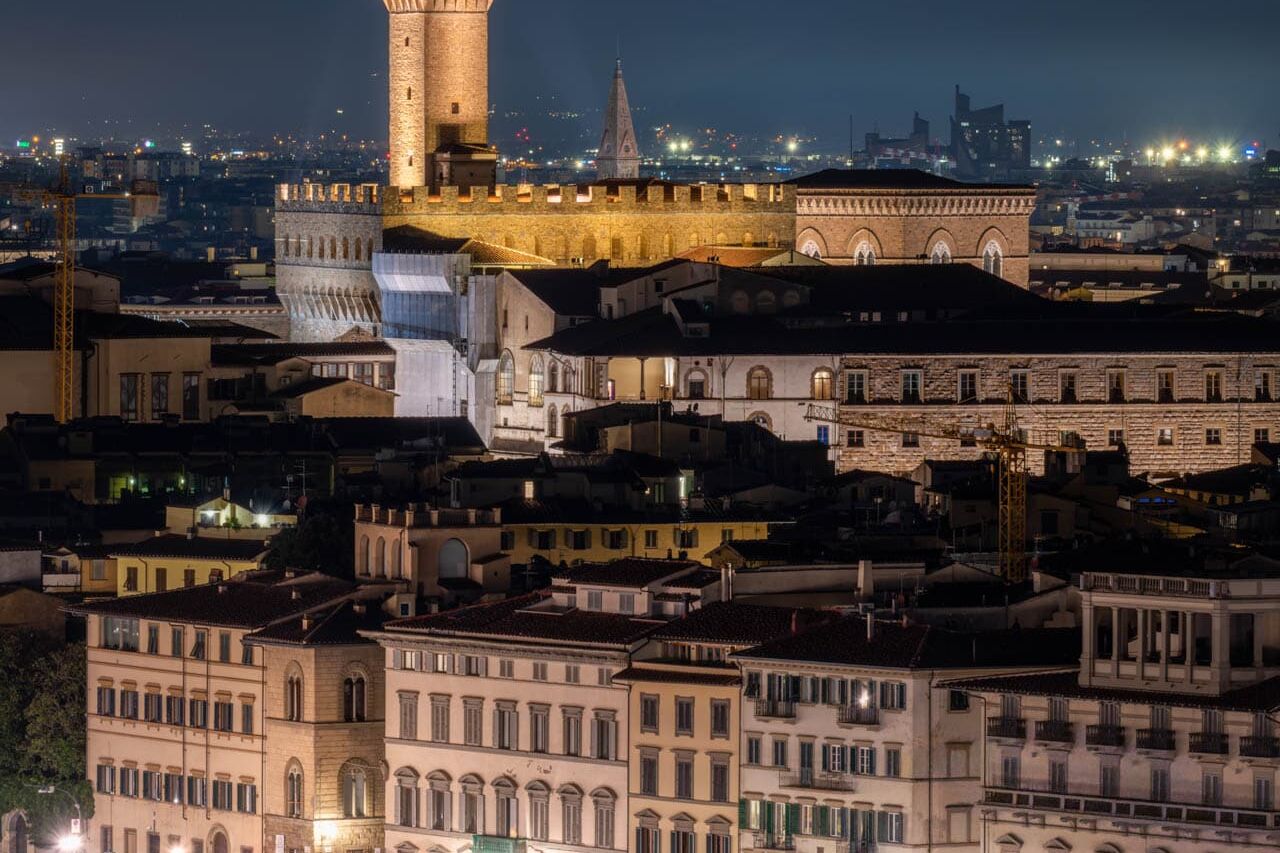 Torre del Mangia bij nacht in Siena, warme amberverlichting met Palazzo Pubblico.