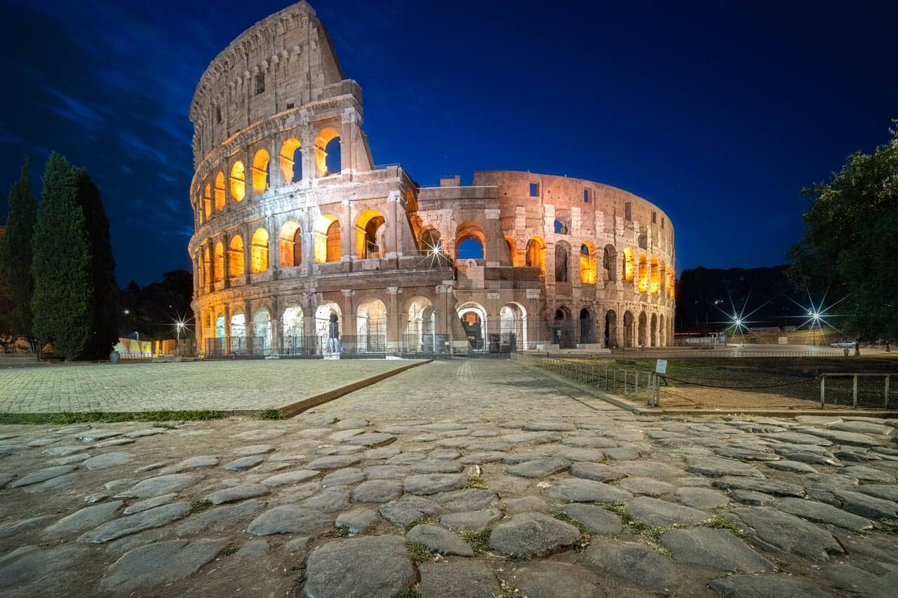 Colosseum bij nacht in Rome met amberkleurig licht en kasseien