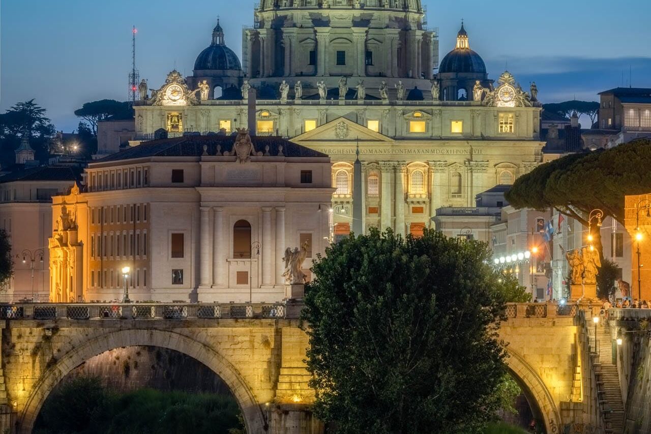 Rome bij nacht: koepel van Sint-Pietersbasiliek boven de Tiber met brug en reflecties