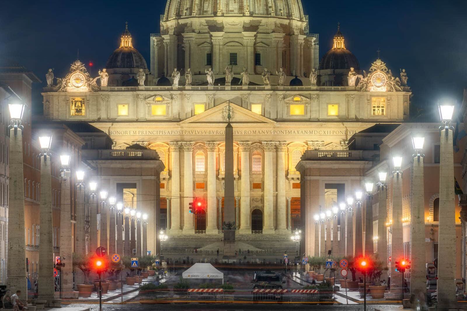 Sint-Pietersbasiliek bij nacht in Rome met verlichte koepel en obelisk op het natte plein.