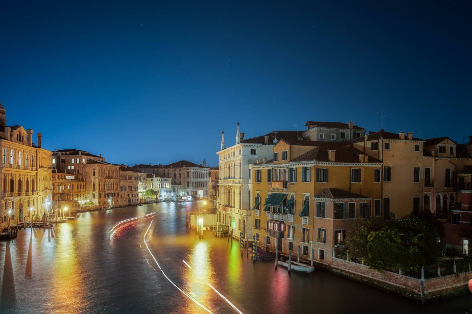Nachtbeeld van Venetië: Italiaanse kanaalstad met warme verlichting en bootsporen