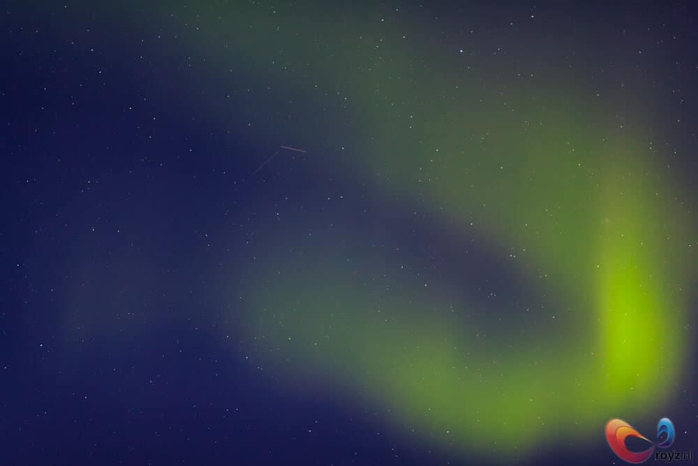 Noorderlicht boven Noorwegen: limegroene linten, sterrenhemel en vallende meteor.