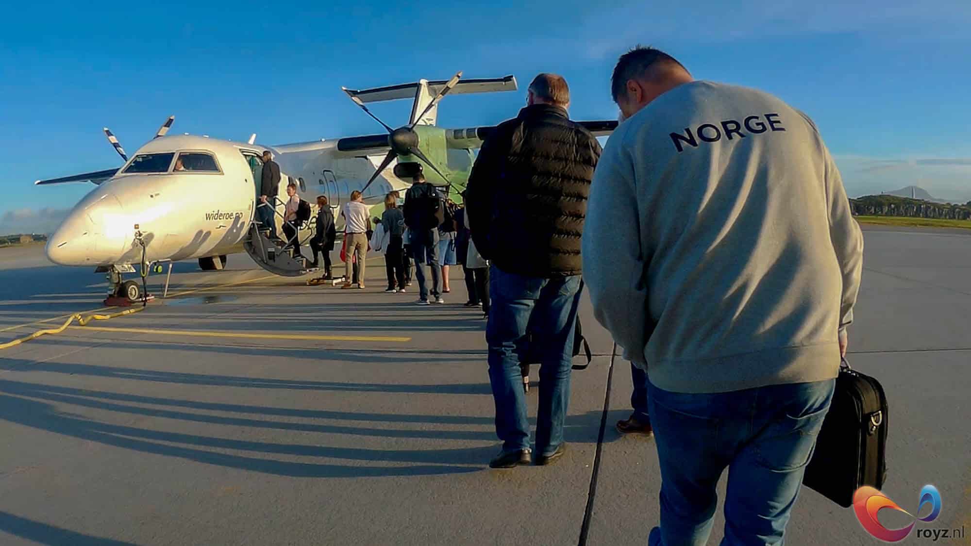 Widerøe vliegtuig bij gouden uur: passagiers in rij voor het instappen.